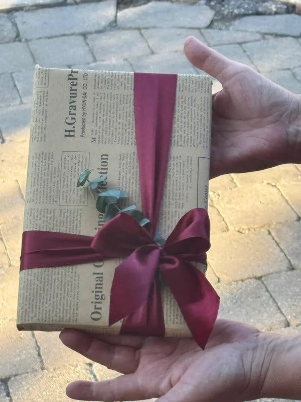Birthday gift wrapped in newspaper wrapping paper with a fresh greenery flower addition