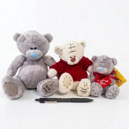Three teddy bears with a pen on a white background